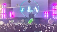 a crowd of people at a concert with a large screen